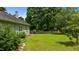 Lush backyard with green grass, mature trees, and a glimpse of the house's exterior at 209 E Winston St, Youngsville, NC 27596
