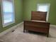 Bright bedroom with a decorative wood bed frame and carpeted floors, illuminated by natural light at 209 E Winston St, Youngsville, NC 27596