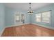 Dining room with wood laminate floors, a modern chandelier, and access to a second room through french doors at 209 E Winston St, Youngsville, NC 27596