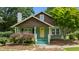 Craftsman-style home with stone chimney, covered front porch, and a yellow front door with well-maintained garden at 209 E Winston St, Youngsville, NC 27596