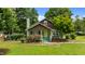 Charming home with stone chimney, covered porch, yellow door, landscaped garden, and well-maintained lawn at 209 E Winston St, Youngsville, NC 27596