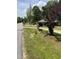Well-maintained front yard with mature trees and landscaping, featuring a for sale sign at 209 E Winston St, Youngsville, NC 27596