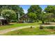 Charming home with lush front yard, mature trees, stone chimney, and a pop of color with a yellow front door at 209 E Winston St, Youngsville, NC 27596