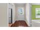 Hallway with wood floors leading to a white exterior door and view into the green accent room and stainless steel refrigerator at 209 E Winston St, Youngsville, NC 27596