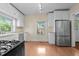 White kitchen features stainless appliances and laminate flooring, illuminated by bright natural light at 209 E Winston St, Youngsville, NC 27596