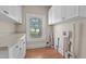 Utility room with laminate flooring, white cabinets, a window, and visible plumbing at 209 E Winston St, Youngsville, NC 27596