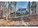 Large backyard is surrounded by mature trees with a white two-story home, trampoline, and deck at 215 Graduate Ct, Durham, NC 27713
