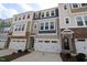 View of townhomes featuring a two-car garage and a mix of siding and stone on the facade at 2323 Hunter Woods Dr # 566, Apex, NC 27502