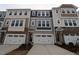 Exterior view of townhomes with two-car garages, varied siding, and decorative stone accents at 2323 Hunter Woods Dr # 566, Apex, NC 27502