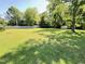 Expansive backyard featuring lush green grass, mature trees, and a storage shed at 2710 Delaney Dr, Burlington, NC 27215
