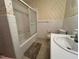 Bathroom featuring tub/shower with glass door, floral wallpaper, and toilet at 2710 Delaney Dr, Burlington, NC 27215