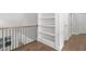 Hallway features hardwood floors, a built-in bookcase, a wood handrail, and white trim at 277 High Ridge Ln, Pittsboro, NC 27312