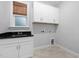 Laundry room features white cabinets, a black sink, tile flooring, and natural light from a window at 277 High Ridge Ln, Pittsboro, NC 27312