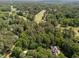Aerial view of a home among mature trees with a golf course in the background at 3203 Rugby Rd, Durham, NC 27707