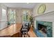 Bright home office featuring a fireplace, large desk, and windows with views of the landscaped exterior at 3203 Rugby Rd, Durham, NC 27707