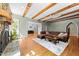 Spacious living room featuring a stone fireplace, wooden beams, hardwood floors, and comfortable seating at 3203 Rugby Rd, Durham, NC 27707