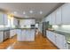 Bright kitchen features white cabinets, stainless steel appliances, dark countertops, and hardwood floors at 325 Hogans Valley Way, Cary, NC 27513
