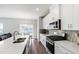 Kitchen with white cabinets, stainless steel appliances, island with bar seating, and view of outdoor dining area at 33 White Ash Dr, Clayton, NC 27527