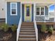Welcoming front entrance with a vibrant yellow door, a charming porch, and neatly arranged landscaping enhancing curb appeal at 353 Rivella Dr, Wake Forest, NC 27587