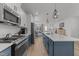 Modern kitchen featuring stainless steel appliances, white countertops, and stylish blue cabinets, perfect for culinary enthusiasts at 353 Rivella Dr, Wake Forest, NC 27587
