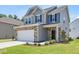 Two-story home featuring stone accents, attached garage, and a well-manicured lawn at 364 Peach Grove Way, Lillington, NC 27546