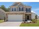 Two-story home featuring stone accents, attached garage, and a well-manicured lawn on a sunny day at 364 Peach Grove Way, Lillington, NC 27546
