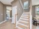 Entryway features a staircase with wooden handrail and white risers, hardwood floors, and a view to the front door at 364 Peach Grove Way, Lillington, NC 27546