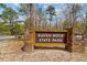 Sign for Raven Rock State Park, a North Carolina State Park, surrounded by trees and natural scenery at 364 Peach Grove Way, Lillington, NC 27546