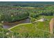 Stunning aerial view of the property featuring a lake, lush greenery, and a beautiful modern home with a swimming pool at 4001 Campbell Rd, Raleigh, NC 27606