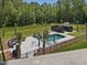 Aerial view of a well-kept in-ground backyard pool, pool house, patio set and palm trees at 4001 Campbell Rd, Raleigh, NC 27606