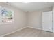 Neutral bedroom with light wood floors, window, and white door at 4204 Green Rd, Raleigh, NC 27604