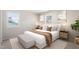 Cozy bedroom with two windows, neutral decor, a bed with many pillows, and hardwood floors at 4204 Green Rd, Raleigh, NC 27604