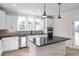 Bright kitchen features white cabinetry, stainless appliances, an island with seating and black countertops at 436 Golden Dragonfly St, Wake Forest, NC 27587