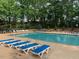Beautiful community pool with sun loungers, surrounded by lush greenery and mature trees at 4910 Briarstone Ct, Raleigh, NC 27610