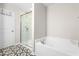 Well-lit bathroom features a soaking tub, glass-enclosed shower, and stylish tile flooring at 513 Commons Dr, Holly Springs, NC 27540