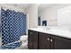 Well-lit bathroom featuring a shower with a decorative blue patterned curtain and dark vanity at 513 Commons Dr, Holly Springs, NC 27540