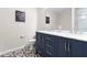 Stylish bathroom with a navy blue vanity, double sinks, decorative mirror, and patterned tile flooring at 513 Commons Dr, Holly Springs, NC 27540