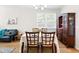 Sunlit dining area with a wood table and seating, illuminated by a modern chandelier and adjacent to living area at 513 Commons Dr, Holly Springs, NC 27540