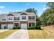 Beautiful townhome featuring a stone facade, red shutters, and a well-manicured lawn and driveway at 513 Commons Dr, Holly Springs, NC 27540