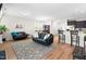Open-concept living room features two leather sofas, a patterned rug, and flows seamlessly into the dining and kitchen areas at 513 Commons Dr, Holly Springs, NC 27540