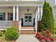 Inviting front porch featuring white columns, brick accents, a welcoming entrance, and vibrant landscaping at 5217 Beckom St, Raleigh, NC 27616