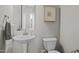 This powder room features a pedestal sink, toilet, wall art, and a decorative towel at 5217 Beckom St, Raleigh, NC 27616