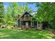 Charming blue house with a spacious wooden porch and balcony, surrounded by lush greenery at 5346 Deep River Rd, Sanford, NC 27330