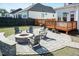 A beautiful backyard with a stone firepit, wood deck and lush green lawn and chairs at 536 Adkins Ridge Rd, Rolesville, NC 27571