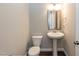Well-lit half bathroom featuring a pedestal sink, mirror, and classic toilet for guest convenience at 536 Adkins Ridge Rd, Rolesville, NC 27571