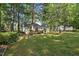 Sprawling backyard featuring healthy lawn with shady tree coverage and the rear exterior of the home at 5414 Stanley Rd, Durham, NC 27704