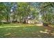 Home's backyard featuring healthy grass, lots of trees, and the rear exterior of the home at 5414 Stanley Rd, Durham, NC 27704