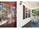 Inviting front porch detail with glass door, white railing, rocking chair, and window with red shutter at 5414 Stanley Rd, Durham, NC 27704