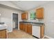 Kitchen featuring wood cabinets, a dishwasher, and laundry area access at 5414 Stanley Rd, Durham, NC 27704