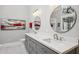 Modern bathroom with double sinks, gray cabinets, and a large round mirror at 55 Fleming Forest Dr, Youngsville, NC 27596